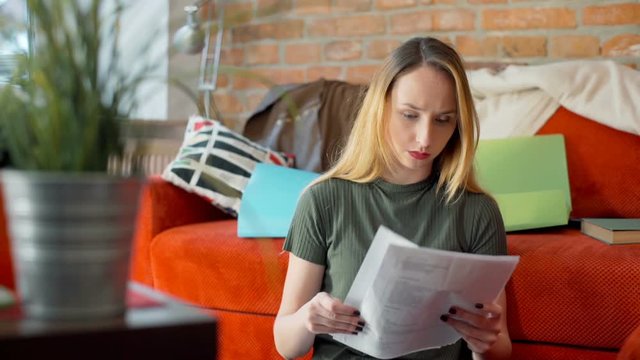 Angry girl reading some documents and tearing them apart
