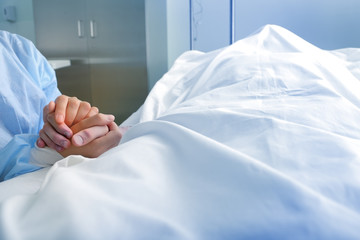 Wife holds the hand of the deceased spouse in the hospital