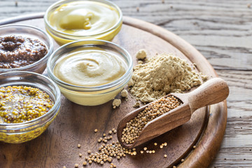 Different kinds of mustard on the wooden background - obrazy, fototapety, plakaty