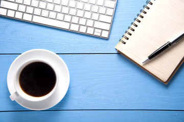 office supplies and cup of coffee on blue wooden table. top view