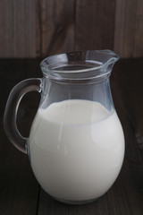 full jug of milk on dark wooden background