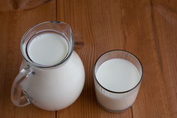 full jug and glass with milk on wooden background