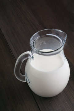 full jug of milk on dark wooden background