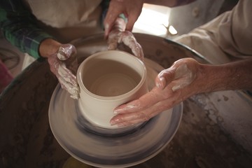 Fototapeta na wymiar Hands of male potter assisting female potter