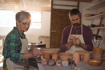 Male and female potter painting pots