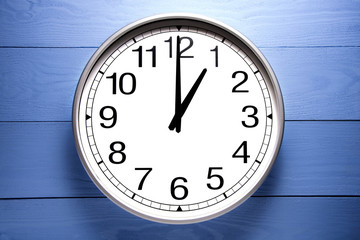 Round clock shows shows at 1 o'clock, clock on blue background