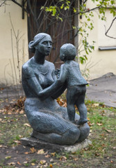Fototapeta na wymiar Городская скульптура молодой женщины с ребёнком на коленях.