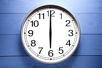 Round clock shows shows at 6 o'clock, clock on blue background