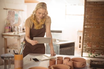 Female potter using digital tablet while working