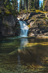 Fototapeta na wymiar Waterfall flowing into a pond. [Portrait]