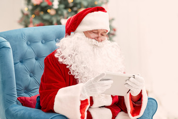 Portrait of happy Santa Claus holding Christmas letter using tab