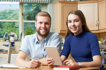 Obraz premium Male Home Tutor Helping Teenage Girl With Studies