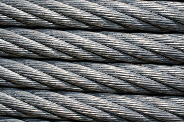 Steel sturdy, heavy duty cable wires.  Up close of cable wire that is wrapped around coil.  Industrial strength wire for tie down or zip line.