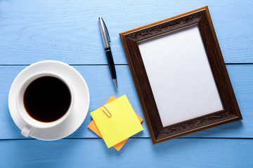 empty photo frames on wooden table with cup of coffee and post it on wooden table background
