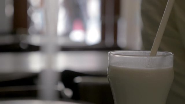 Close-up shot of a person in having refreshing horchata drink using straw. Traditional Spanish beverage made of nutsedge