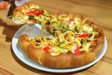 Seafood Italian Pizza slice on wood table in fastfood restaurant
