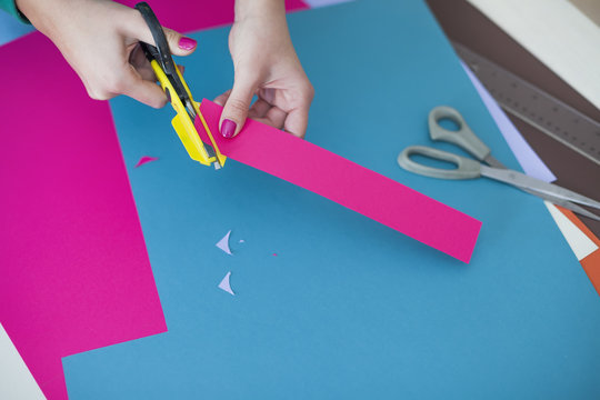 Young woman make scrapbook of the papers on the table using antique tools for cutting paper. Hand made photo album.Shallow depth of field