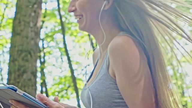 Happy young girl enjoy roller skating rollerblading on inline skates in park. Woman in outdoor activities and listening to music from the tablet.
