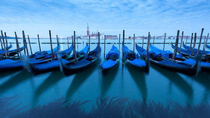 View of Gondolas tied up at the side of the grand canal waiting on tourists. Showing view over the Grand Canal in Venice.