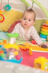 Fototapeta premium Eight months old baby girl playing with colorful toys on a floor