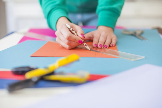 Young woman make scrapbook of the papers on the table using antique tools for cutting paper. Hand made photo album.Shallow depth of field