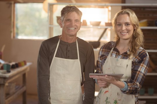 Potters using digital tablet in pottery workshop