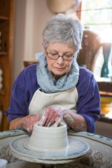 Attentive female potter making pot