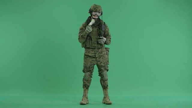 Soldier standing and giving money to camera at green screen
