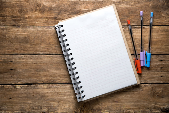Open Blank Page notebook and pens on wooden table background