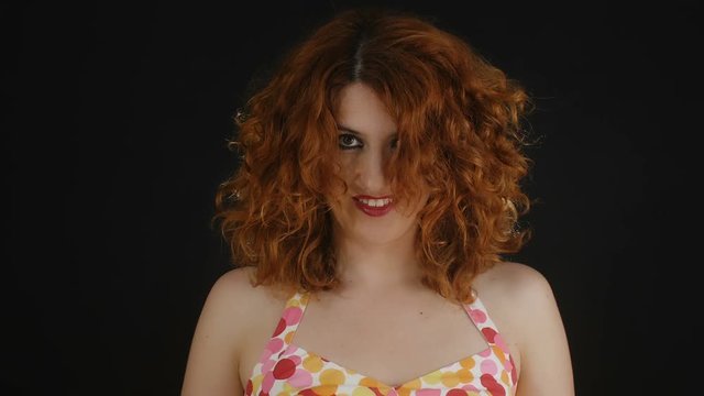 smiling young woman shakes her red hair