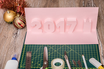 Making  pop-card  in the form of 2017 year. Card and tools  used for its construction on cutting mat.
