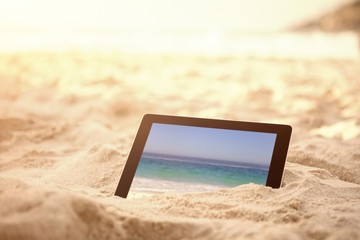 Composite image of digital tablet kept on sand at beach - Powered by Adobe