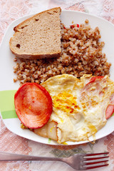 dish from boiled buckwheat fried piece of sausage and fried eggs