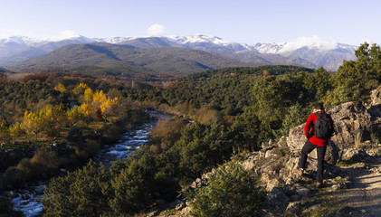 Fototapeta na wymiar Senderista a los pies de montañas nevadas en el sistema central y río Tietar desde Madrigal de la Vera