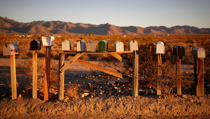 Several mailboxes in the desert during sunset
