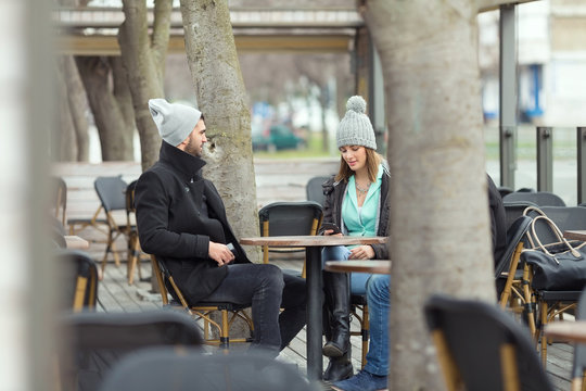 Group of students or young business people is sitting in an outdoor café on a cold winter day.