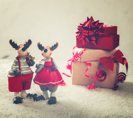 Christmas Gifts in Red and beige Boxes Tied with Festive Ribbons on a White Background in the Snow with Toys Moose with Christmas tree.selective focus .Copy space.Toned image.Vintage style.