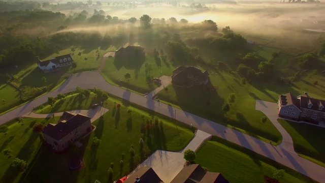 Beautiful neighborhoods, homes, suburbs, under spectacular foggy sunrise, aerial view.