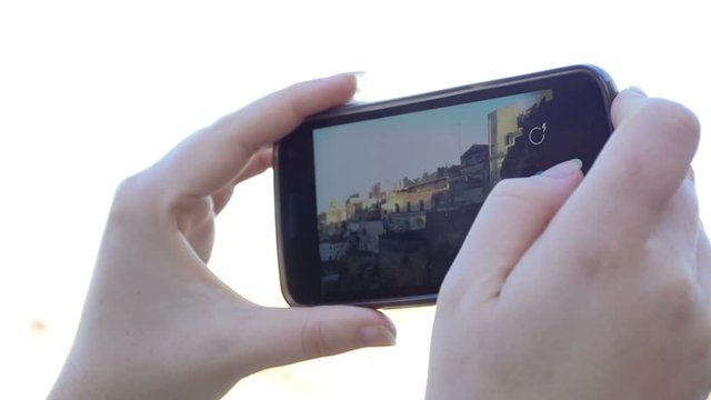 woman is taking pictures with the smartphone: tourist, tourism, Italy, Matera