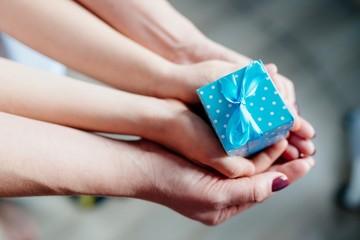 Hands of mother and child holding little box