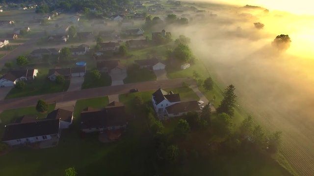 Beautiful neighborhoods, homes, suburbs, under spectacular foggy sunrise, aerial view.