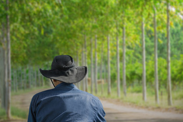 Man wearing jean jecket and black hat standing look background of trees.