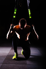 One young handsome brave curly bearded muscled man with a beard makes Total Resistance eXercises fitness trx straps working out in gym crossfit