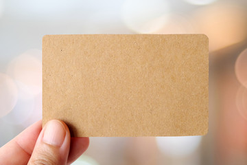 Hand holding blank recycle paper name card over blur background, template, business concept