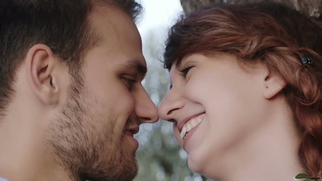 man and woman kissing in the park: young people in love having a flirt