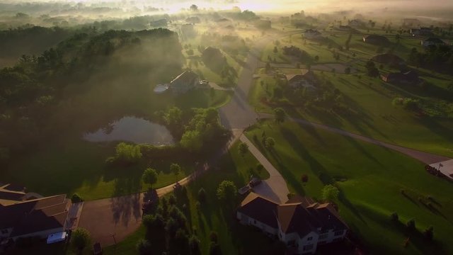 Beautiful neighborhoods, homes, suburbs, under spectacular foggy sunrise, aerial view.