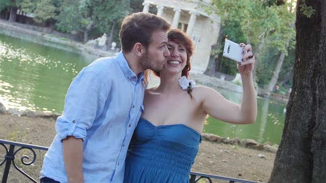 young couple is  making selfie at the park near a romantic lake
