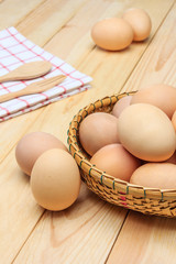 Fresh egg in the basket weaving over wooden table background, Closed up