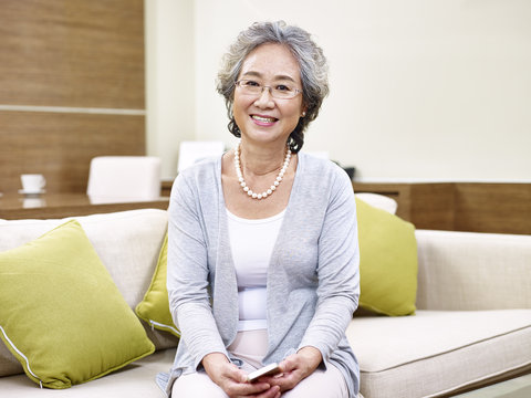 portrait of senior asian woman sitting on couch at home