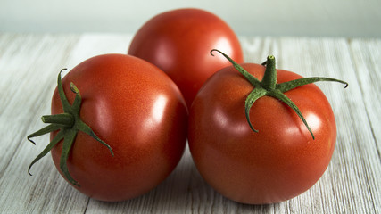 three red tomatoes on wood table